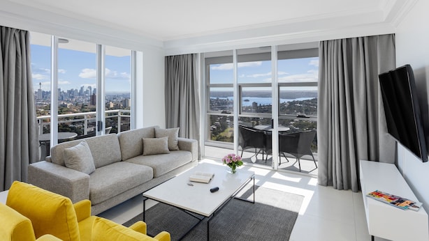 A modern living room with a sofa, yellow chairs, a coffee table, and a TV. - Meriton Suites Bondi Junction (Bondi Junction)