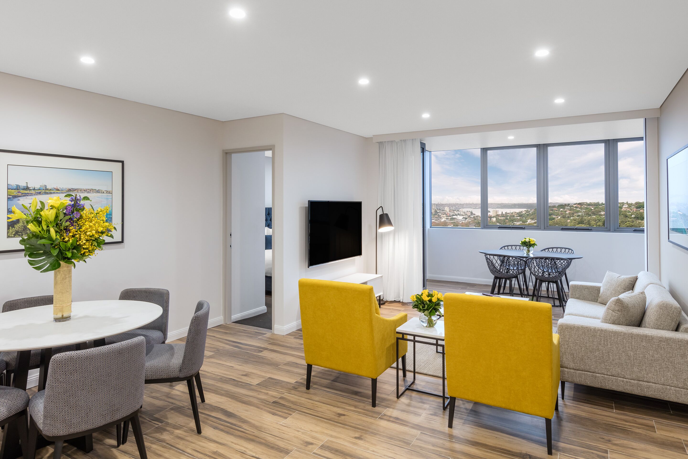 A modern living room with a dining area, a sofa, and a TV.