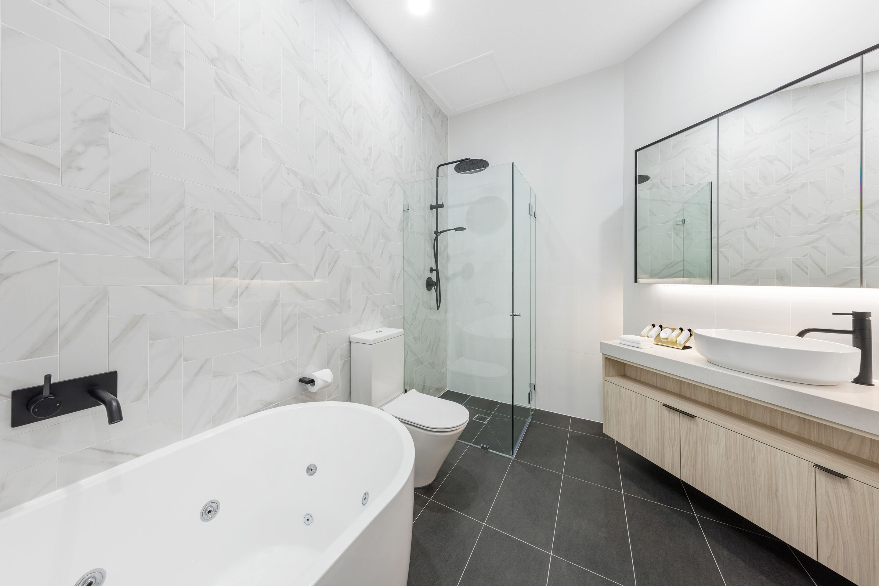 A modern bathroom with a freestanding bathtub, a glass-enclosed shower, a toilet, and a vanity with a mirror.