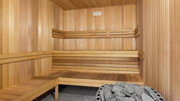 Un sauna avec des bancs en bois et un récipient en métal rempli de pierres.