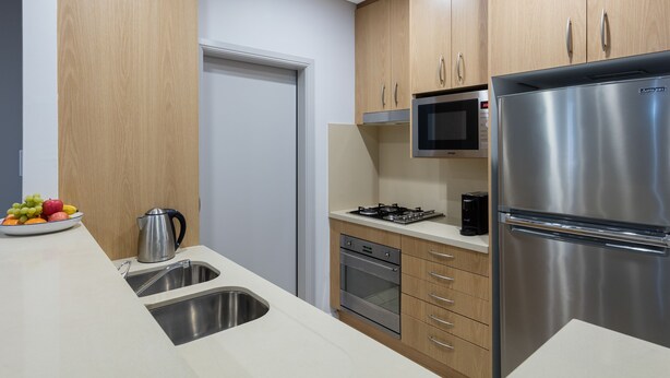 A modern kitchen with stainless steel appliances, wooden cabinets, and a built-in microwave.