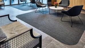 Eine großzügige Lobby mit moderner Sitzgelegenheiten, großen Fenstern und einem Flachbildfernseher an der Wand.