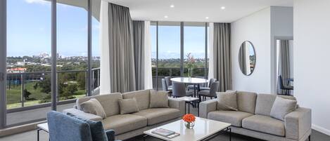 A modern living room with a large window, two sofas, a coffee table, and a dining area.