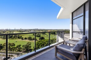 Un balcon offrant une vue sur un paysage verdoyant et sur la ville.