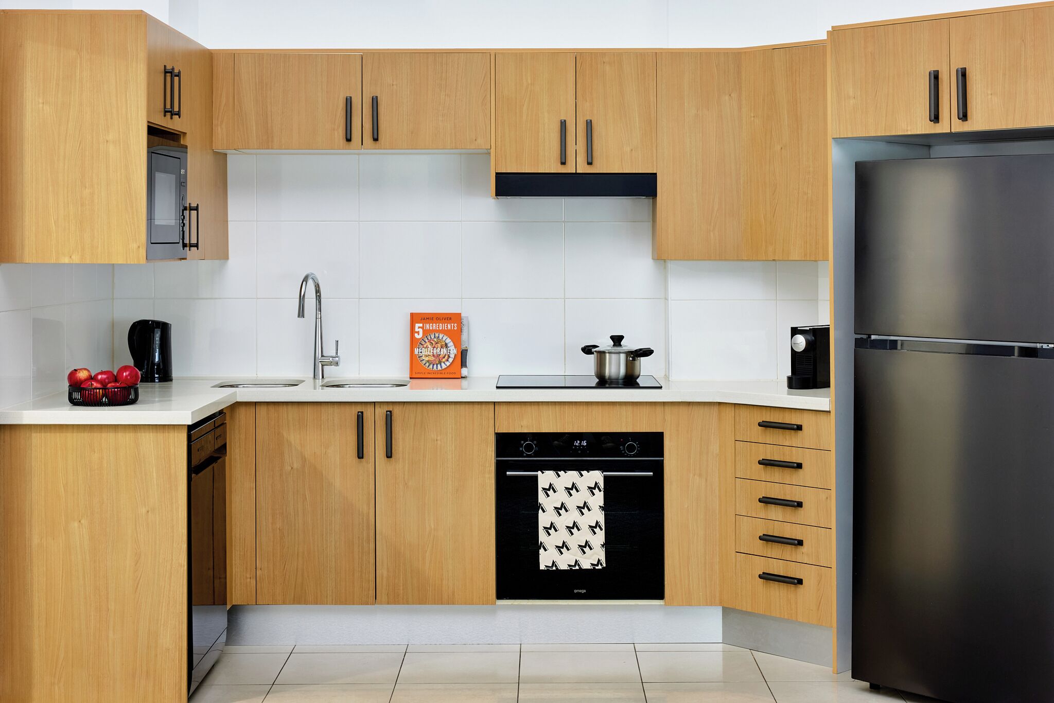 A modern kitchen with wooden cabinets, a stainless steel refrigerator, a dishwasher, and a microwave.