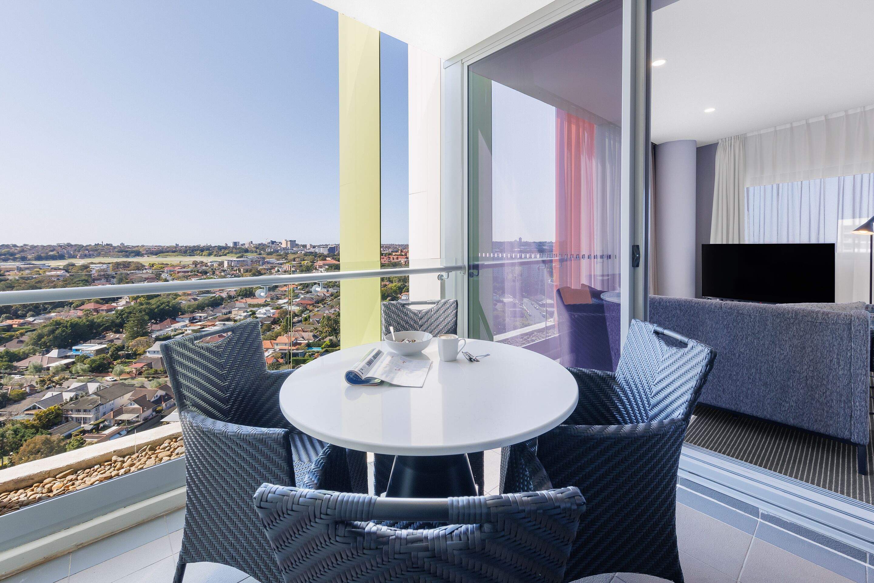 A balcony with a table and chairs, a sofa, and a TV.