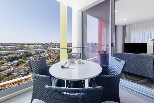 A balcony with a table and chairs, a sofa, and a TV.