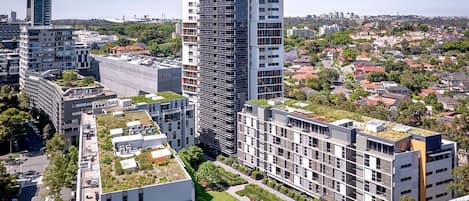 A modern high-rise building with multiple balconies and a rooftop garden.