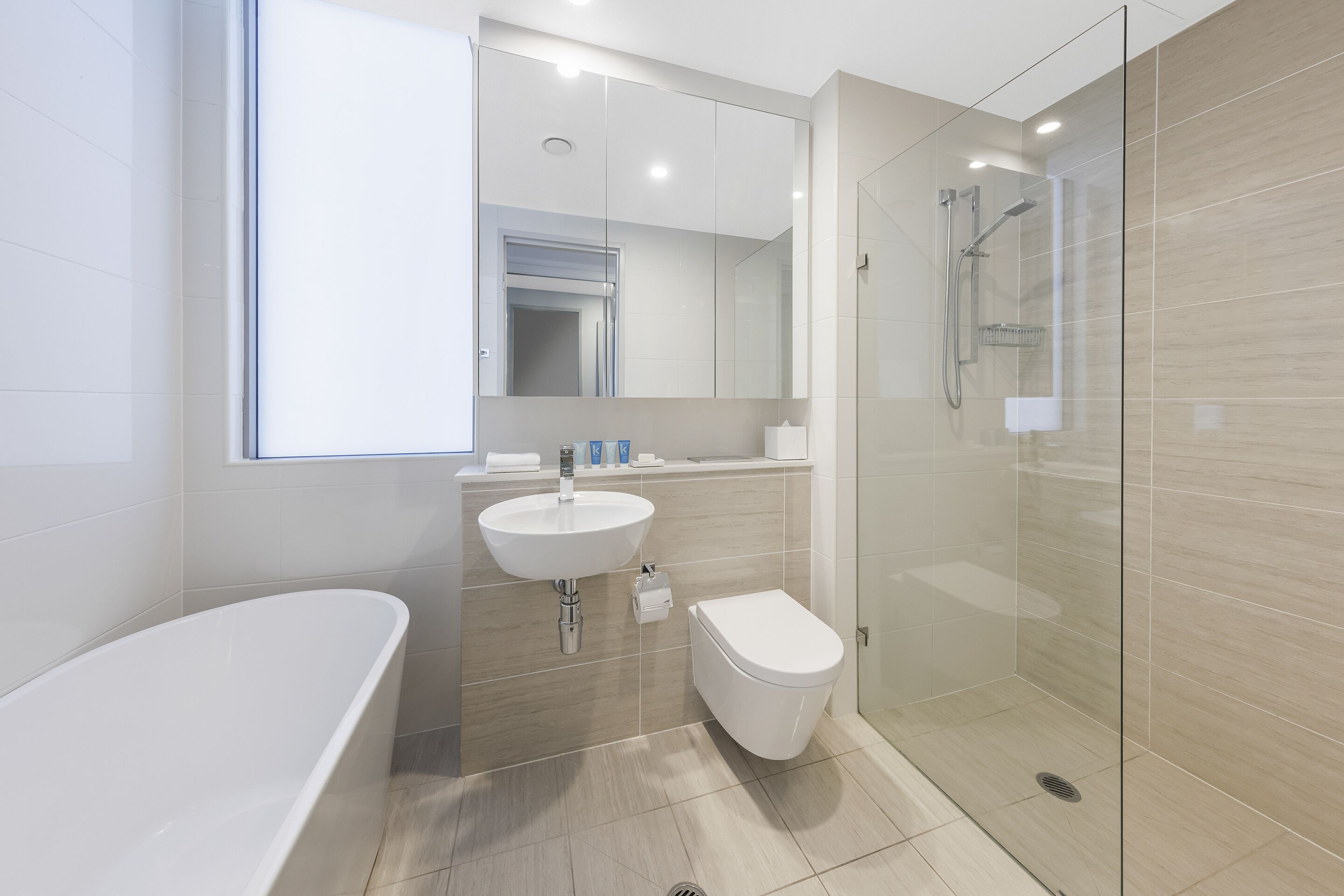 Une salle de bain moderne avec une baignoire sur pieds, un lavabo, des toilettes et une douche séparée par des parois en verre.