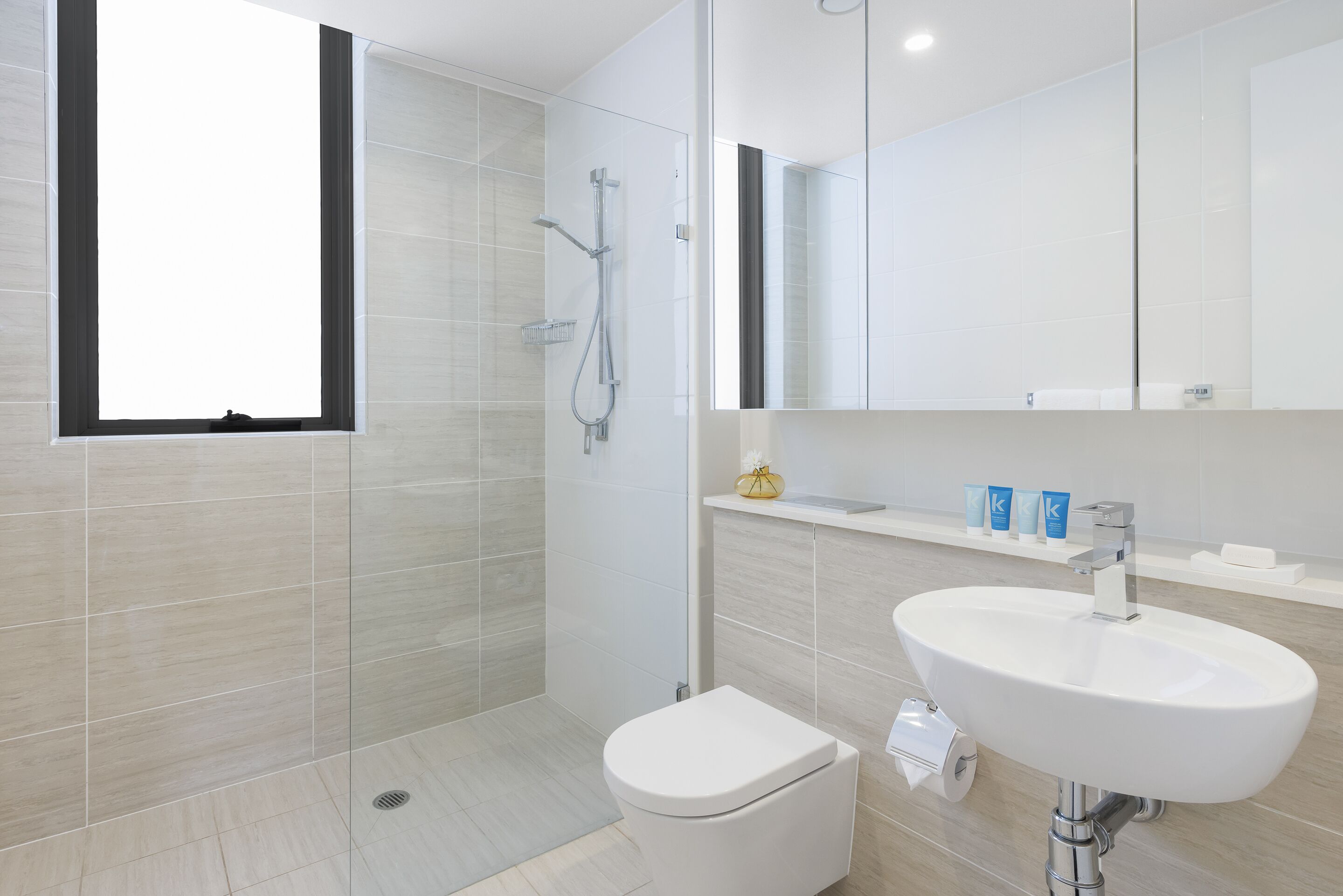 A modern bathroom with a shower, toilet, and sink.