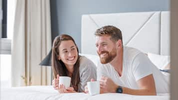 Una pareja recostada en una cama en una habitación de hotel con un cabecero moderno y una lámpara de noche.