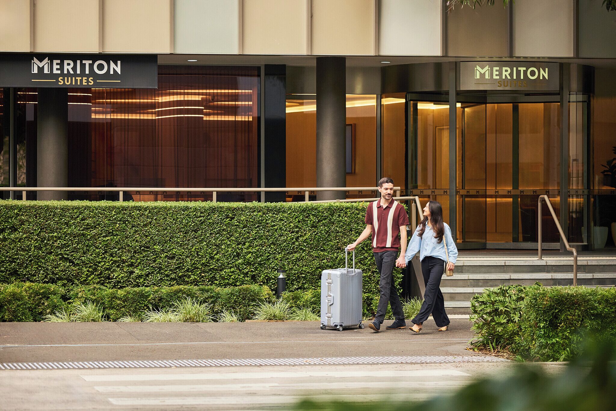 A hotel entrance with a sign reading 'Meriton Suites.'