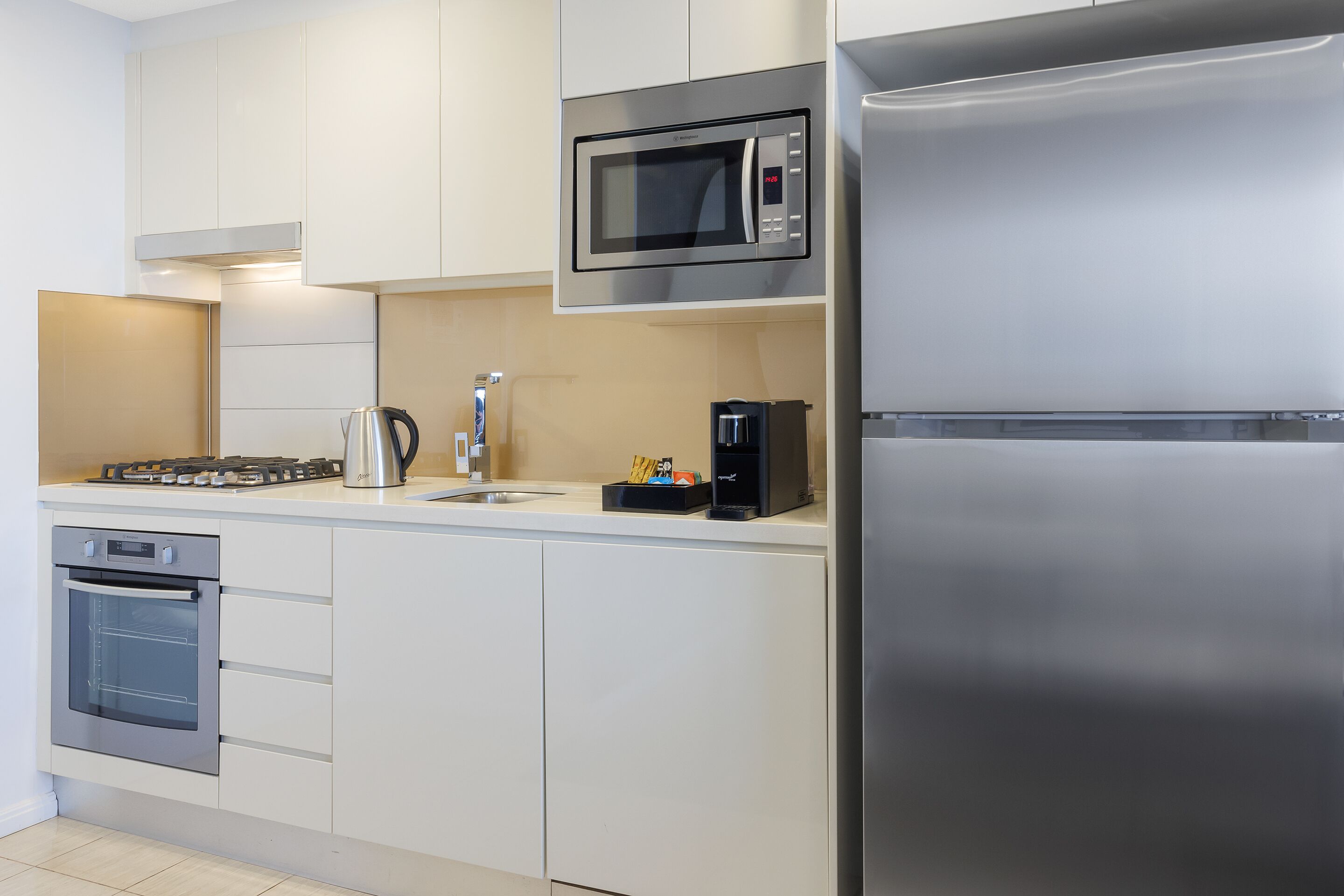 Een moderne keuken met roestvrijstalen apparatuur, waaronder een magnetron, oven en koelkast.