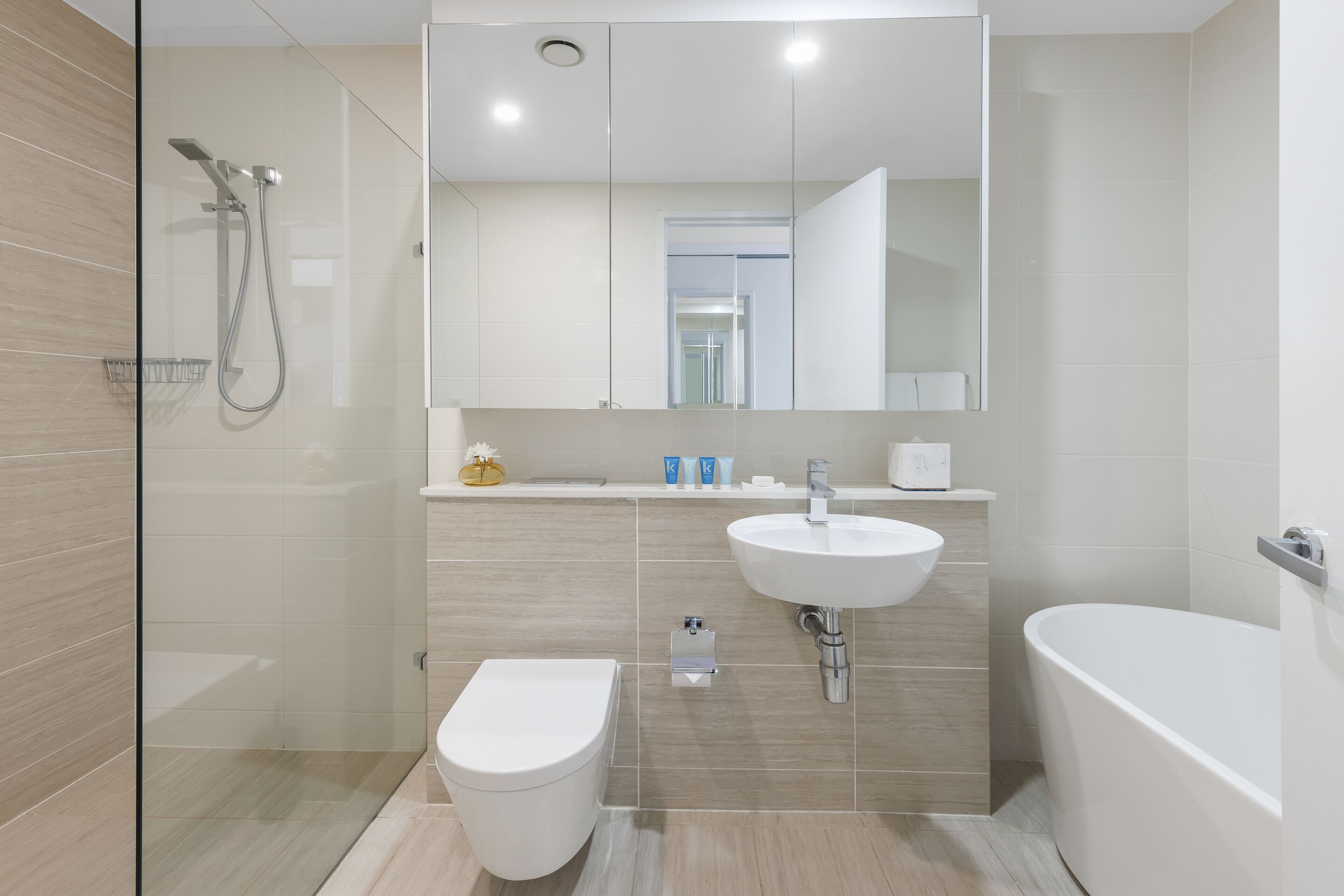 Ein modernes Badezimmer mit einer Duschkabine, einer weißen Toilette, einem Waschbecken und einer Badewanne.
