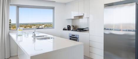 A modern kitchen with a large island, stainless steel appliances, and a view of the city.