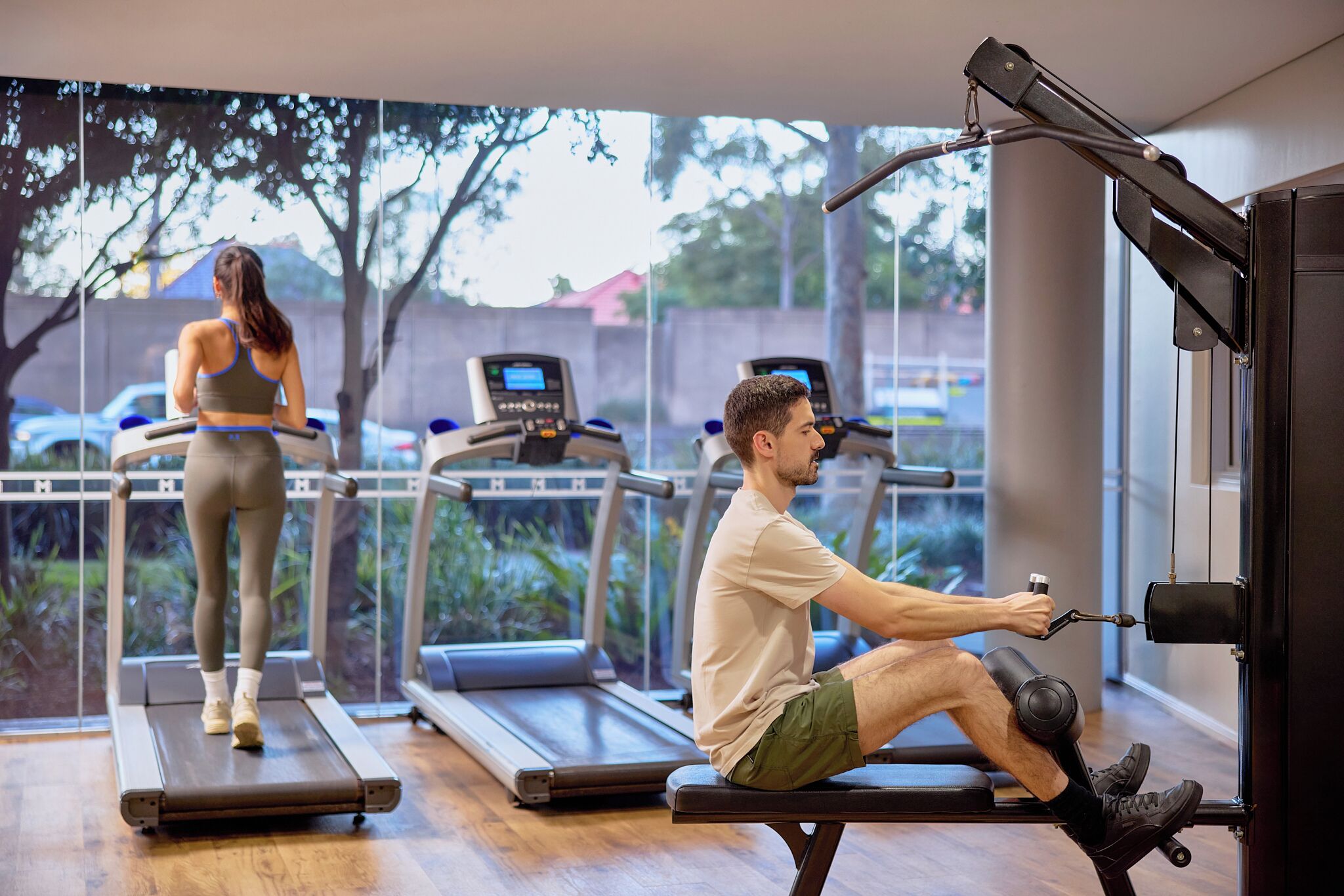 Un gimnasio con cintas de correr, una máquina de remo y una persona usando la máquina.