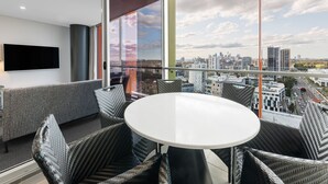 Un balcón moderno con mobiliario de mimbre, un televisor de pantalla plana y vistas a la ciudad.