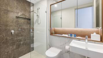 A modern bathroom with a glass-enclosed shower, a white toilet, and a marble sink.