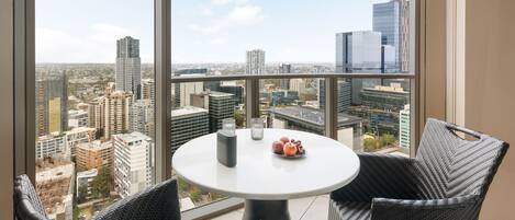 A balcony with a round table, wicker chairs, and a fruit bowl.