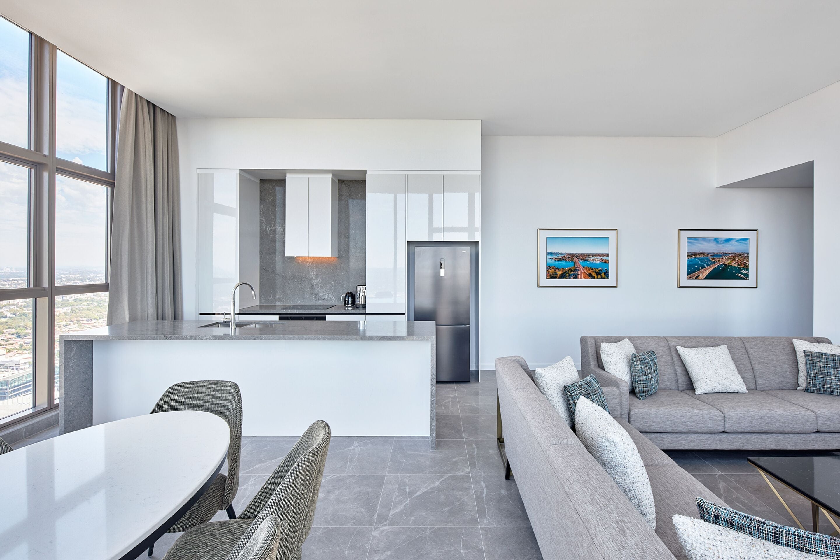 Un espacio habitable moderno con una isla de cocina, comedor y un conjunto de sofás.