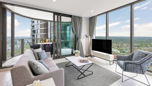 Ein modernes Wohnzimmer mit einem grauen Sofa, einem gemusterten Sessel, einem Couchtisch und einem Flachbildfernseher.