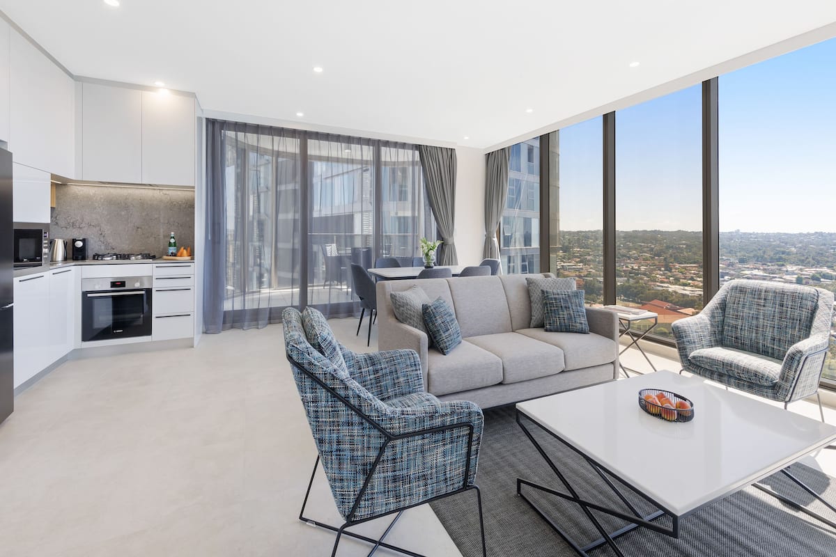A modern apartment with a kitchen, living area, and large windows offering a city view.