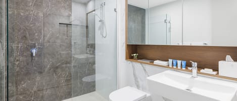 A modern bathroom with a glass-enclosed shower, a white toilet, and a large sink with a wooden countertop.