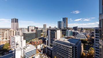 A cityscape with modern high-rise buildings, a construction crane, and a clear blue sky.