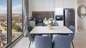 Eine moderne Küche mit weißen Schränken, einem Edelstahlkühlschrank und einer Essecke mit Tisch und Stühlen.