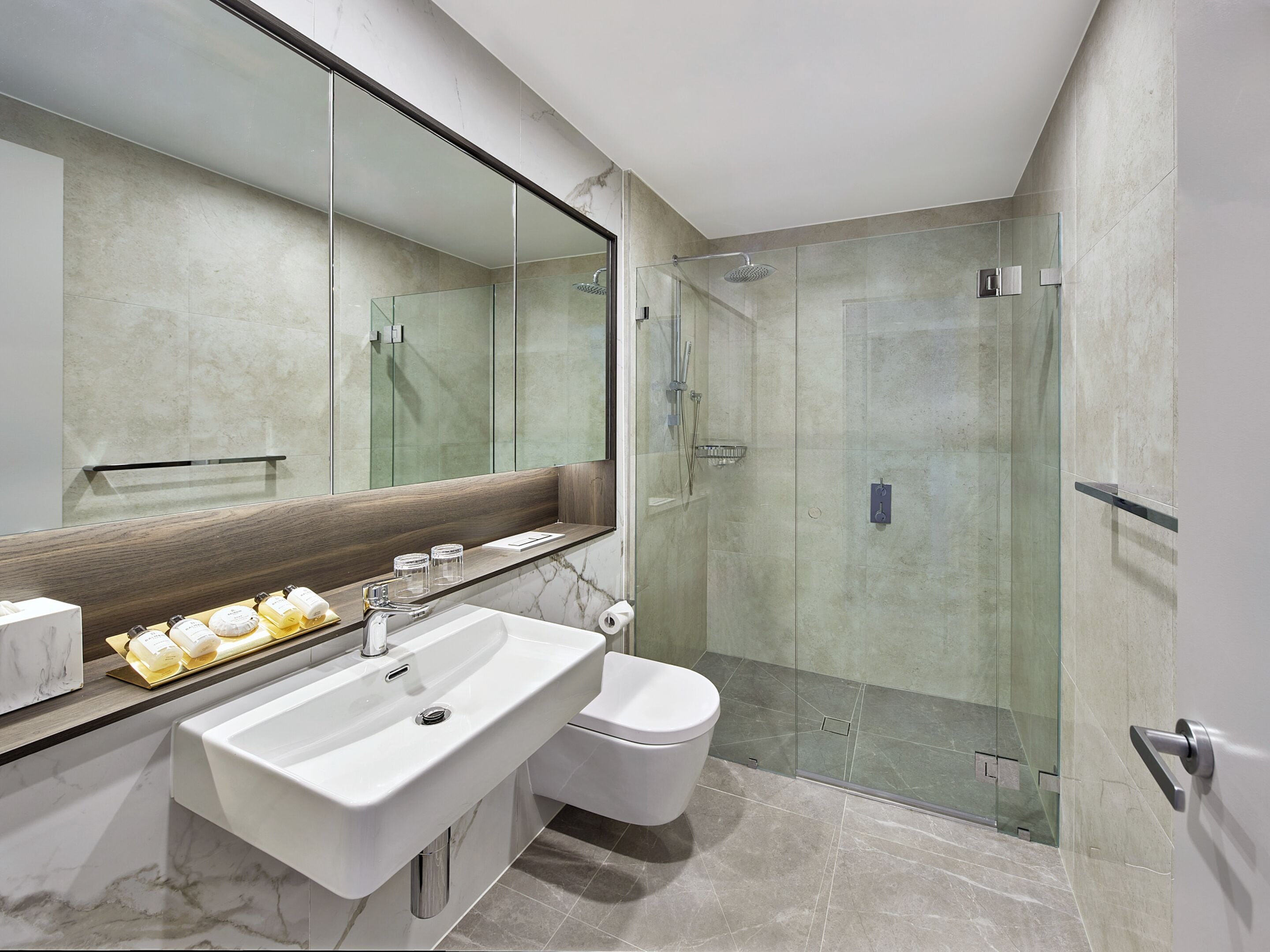 Ein modernes Badezimmer mit großem Spiegel, Waschbecken, Toilette und einer Duschkabine.