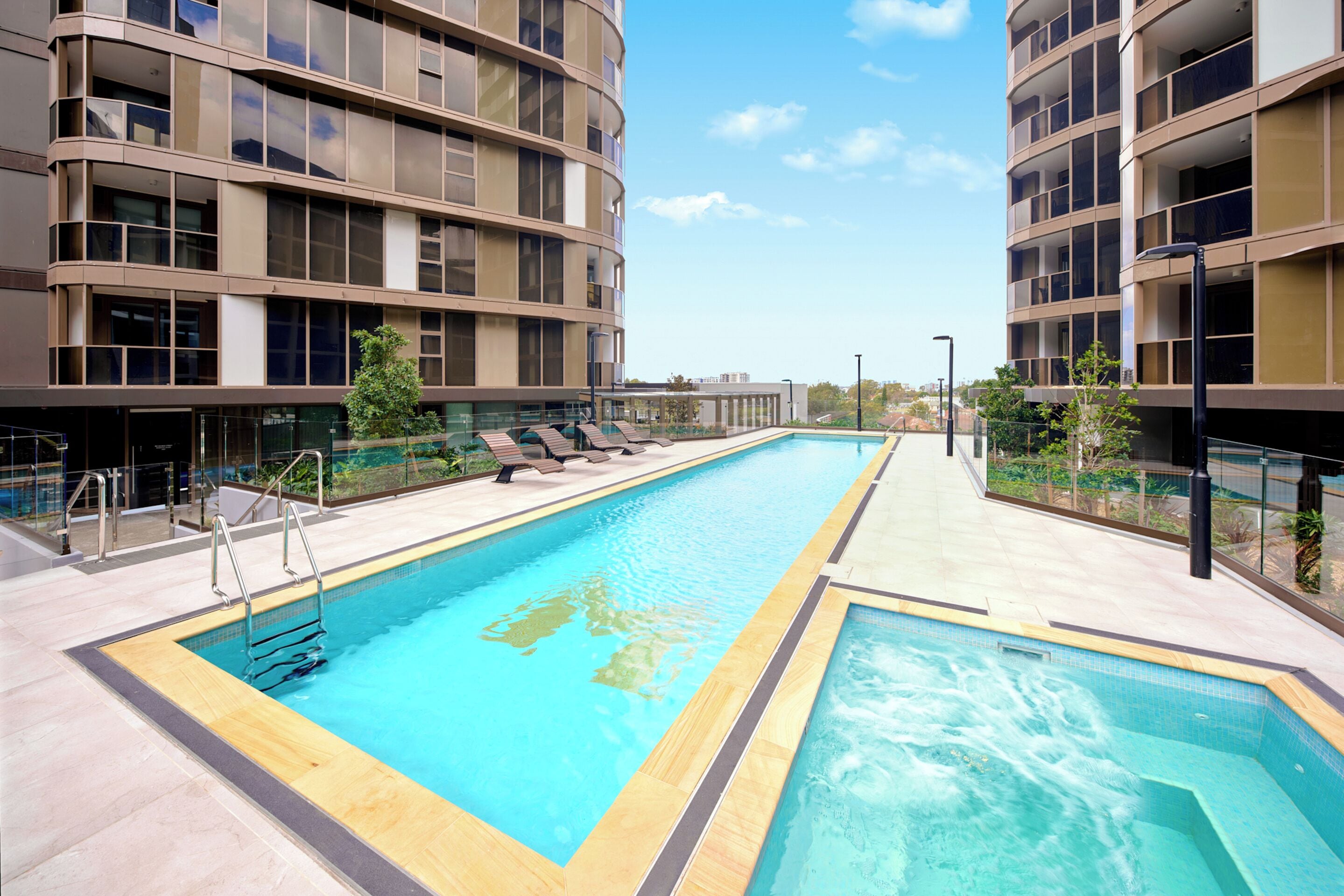 Un hotel moderno con piscina, tumbonas y vistas del entorno.