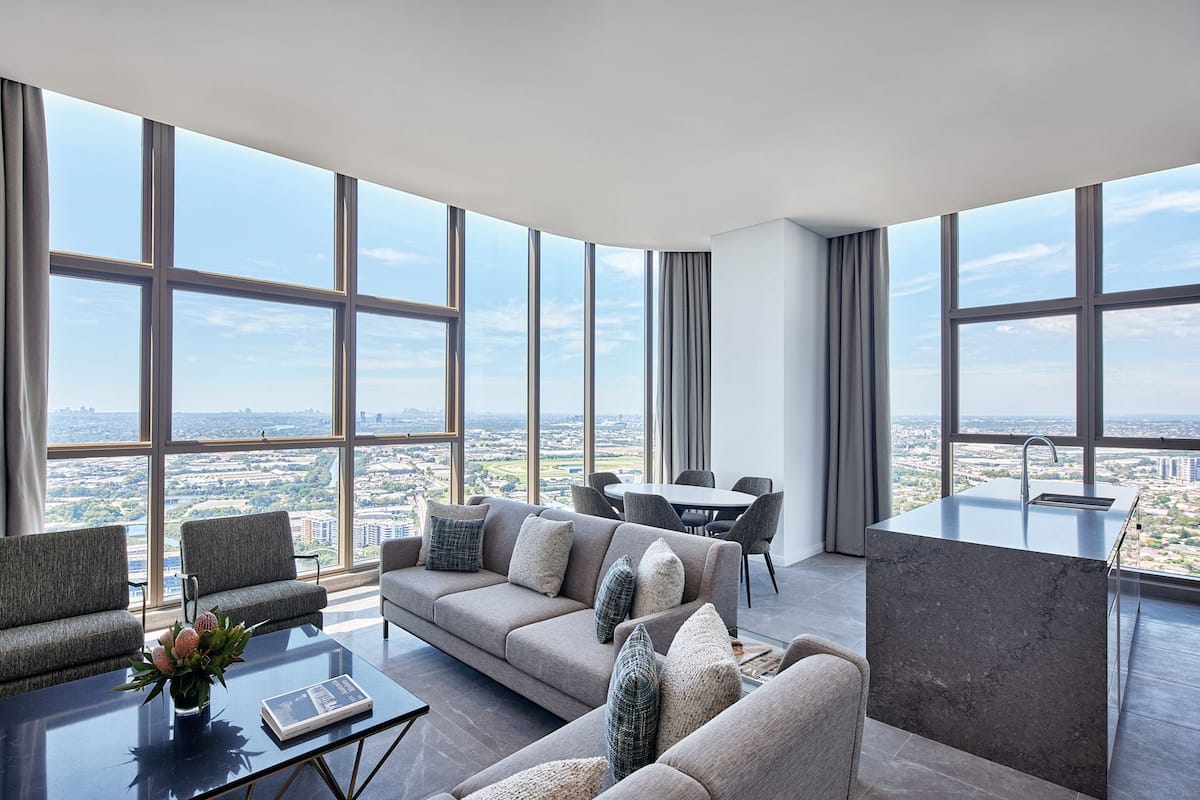 A modern living room with a large window, a sofa, a coffee table, and a dining area.