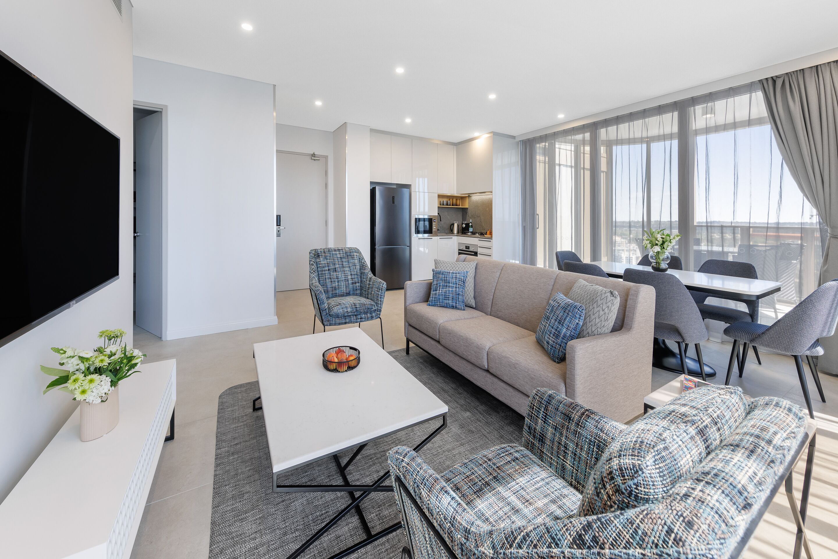 A modern living room with a sofa, chairs, a coffee table, and a TV.