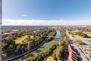Vista aérea de un paisaje urbano con un río, un puente y zonas verdes circundantes.