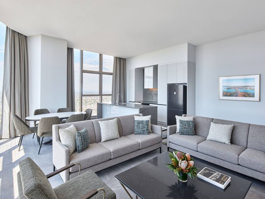 A modern living room with a grey sofa, a coffee table, and a dining area with chairs.
