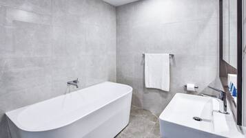 A modern bathroom with a freestanding bathtub, a sink, and a mirror.