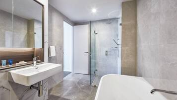 A modern bathroom with a large mirror, a white sink, a glass-enclosed shower, and a white bathtub.