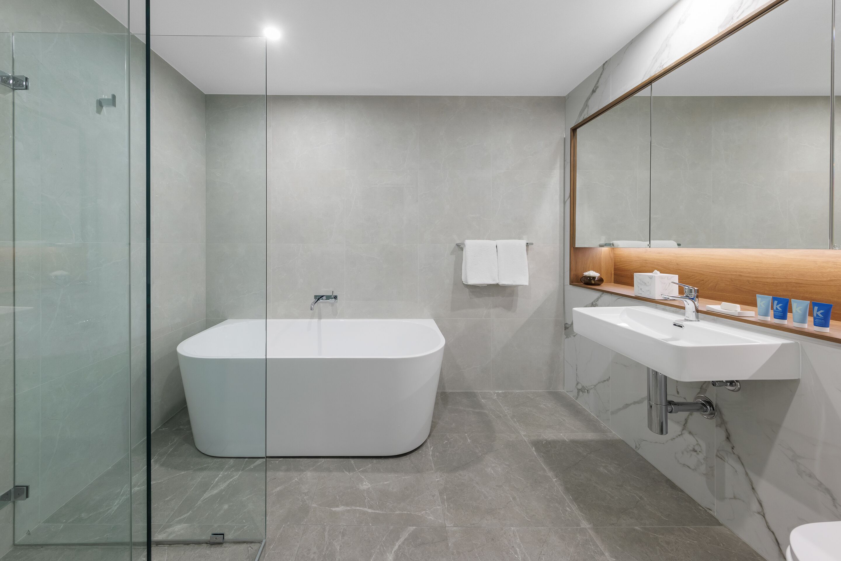 A modern bathroom with a freestanding bathtub, a vanity with a mirror, and a glass shower enclosure.