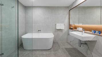 Un baño moderno con una bañera independiente, un tocador con espejo y un box de ducha de vidrio.