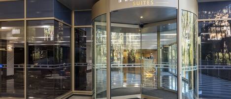 L’entrée d’un hôtel, avec une porte tournante en verre et une enseigne indiquant « Meriton Suites ».