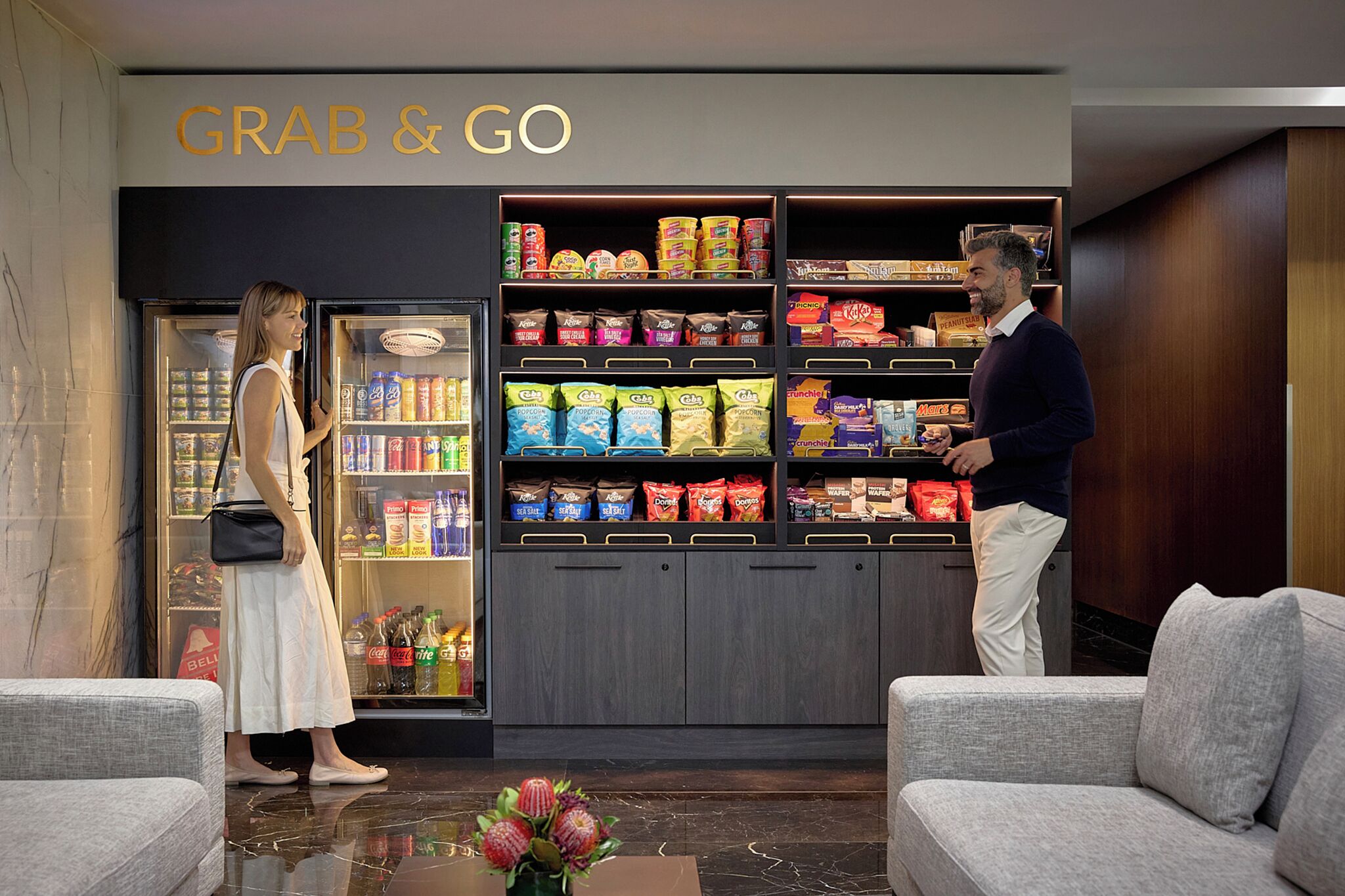A hotel lobby with a 'GRAB & GO' snack station and seating area.