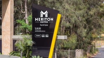 Schild für das Meriton Suites North Ryde mit Kontaktinformationen und Icons für Studios.