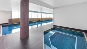 Una piscina con suelo de baldosas y una gran columna en el centro.
