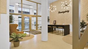 Ein moderner Empfangsbereich mit Wandverkleidung aus Holz-Fischgrätmuster, einer Chandelüster und einer Sitzecke mit Bar.