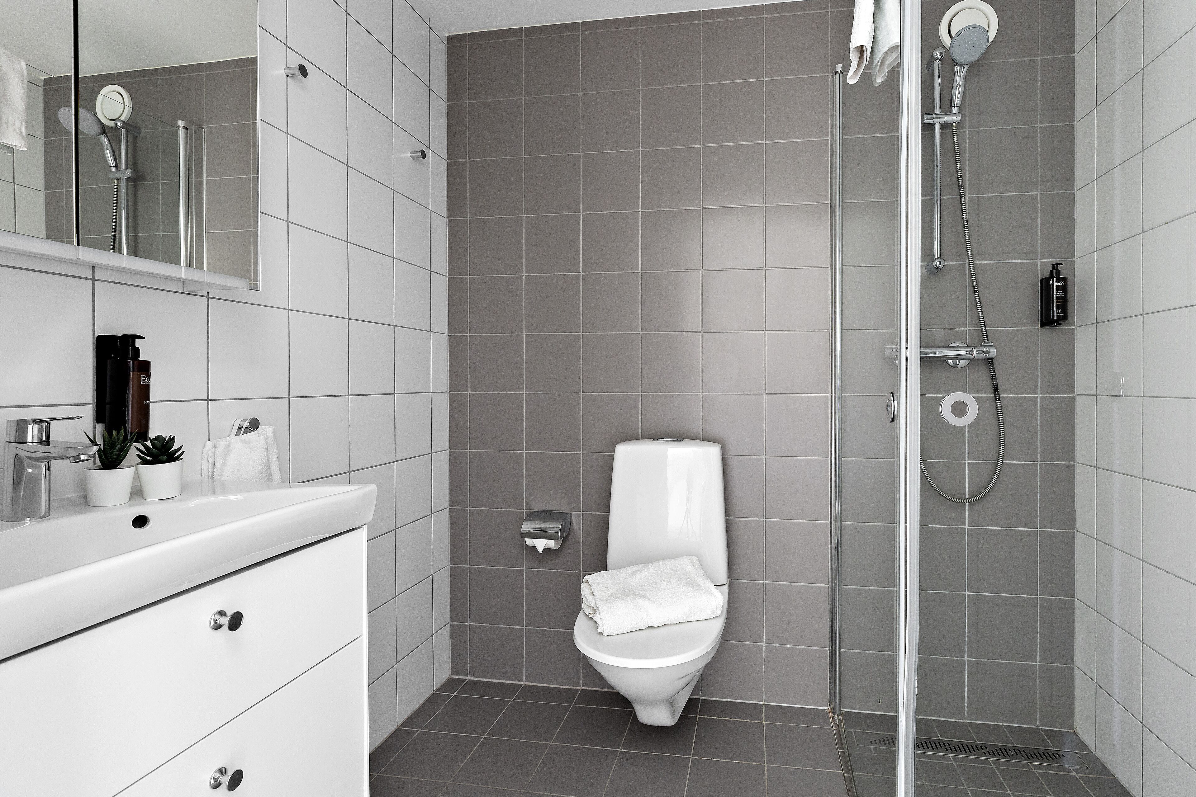 Een moderne badkamer met een wit wastafel, toilet en douche.