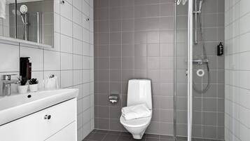 Een moderne badkamer met een wit wastafel, toilet en douche.