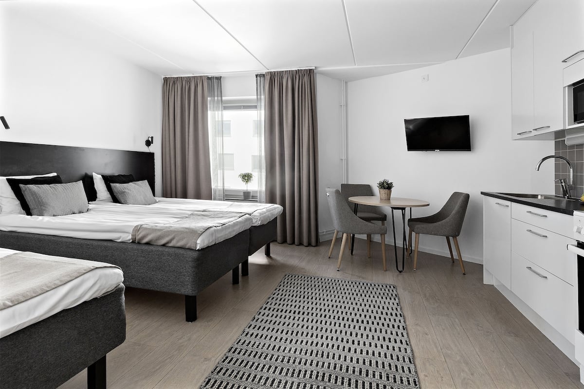 Une chambre d’hôtel moderne équipée d’un grand lit, d’un bureau, d’une chaise, d’une télévision et d’une kitchenette.