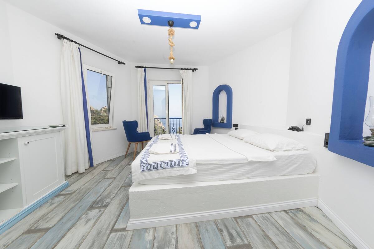 A bedroom with a bed, a TV, a desk, and a chair.