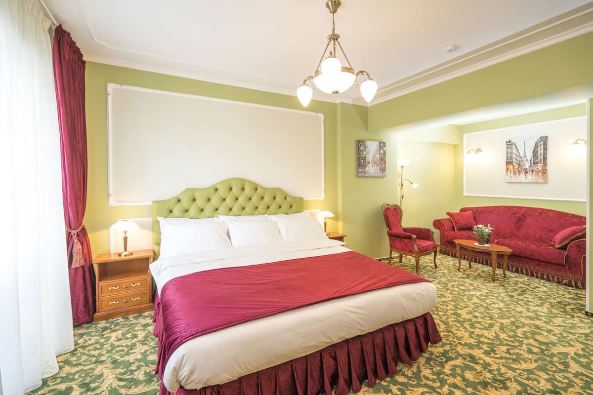 Une chambre d’hôtel avec un grand lit, un canapé rouge, une chaise et un bureau.