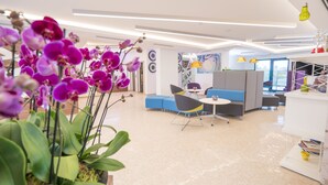 Een modern interieur met een zithoek, een witte receptiebalie en een groot raam met uitzicht.